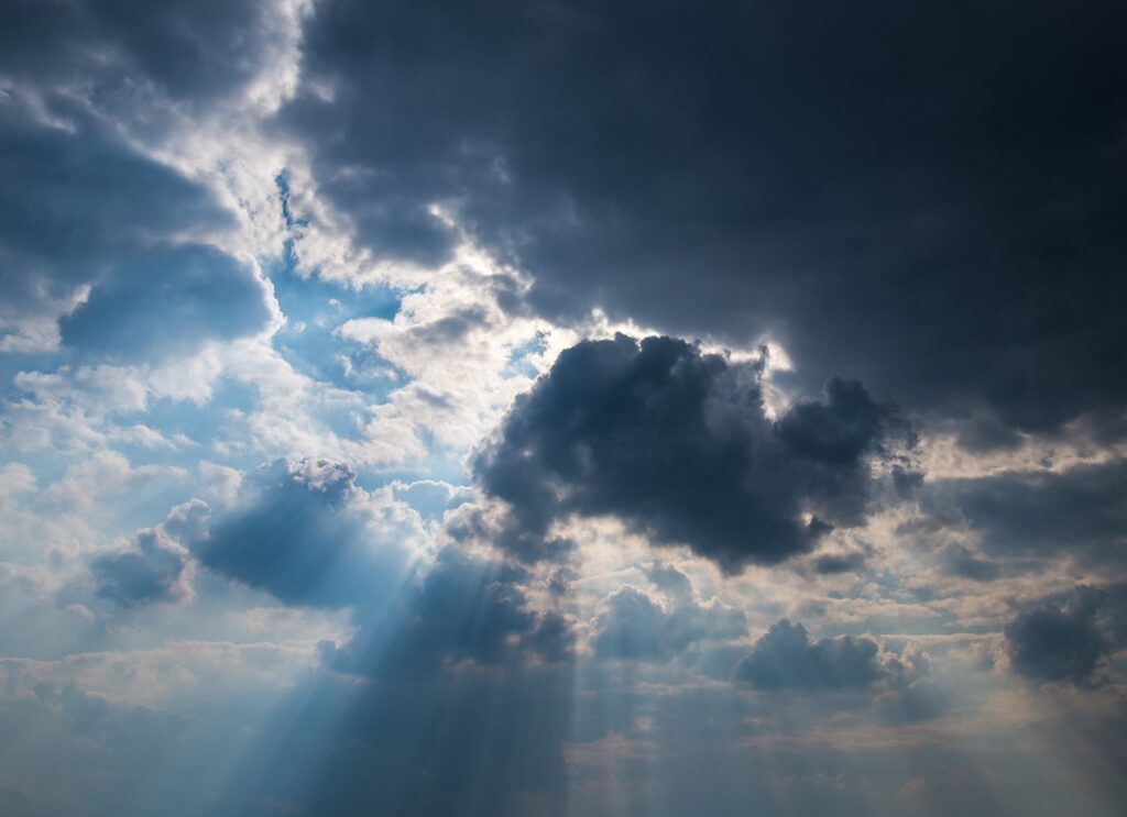 Molnig himmel med solstrålar som skiner igenom